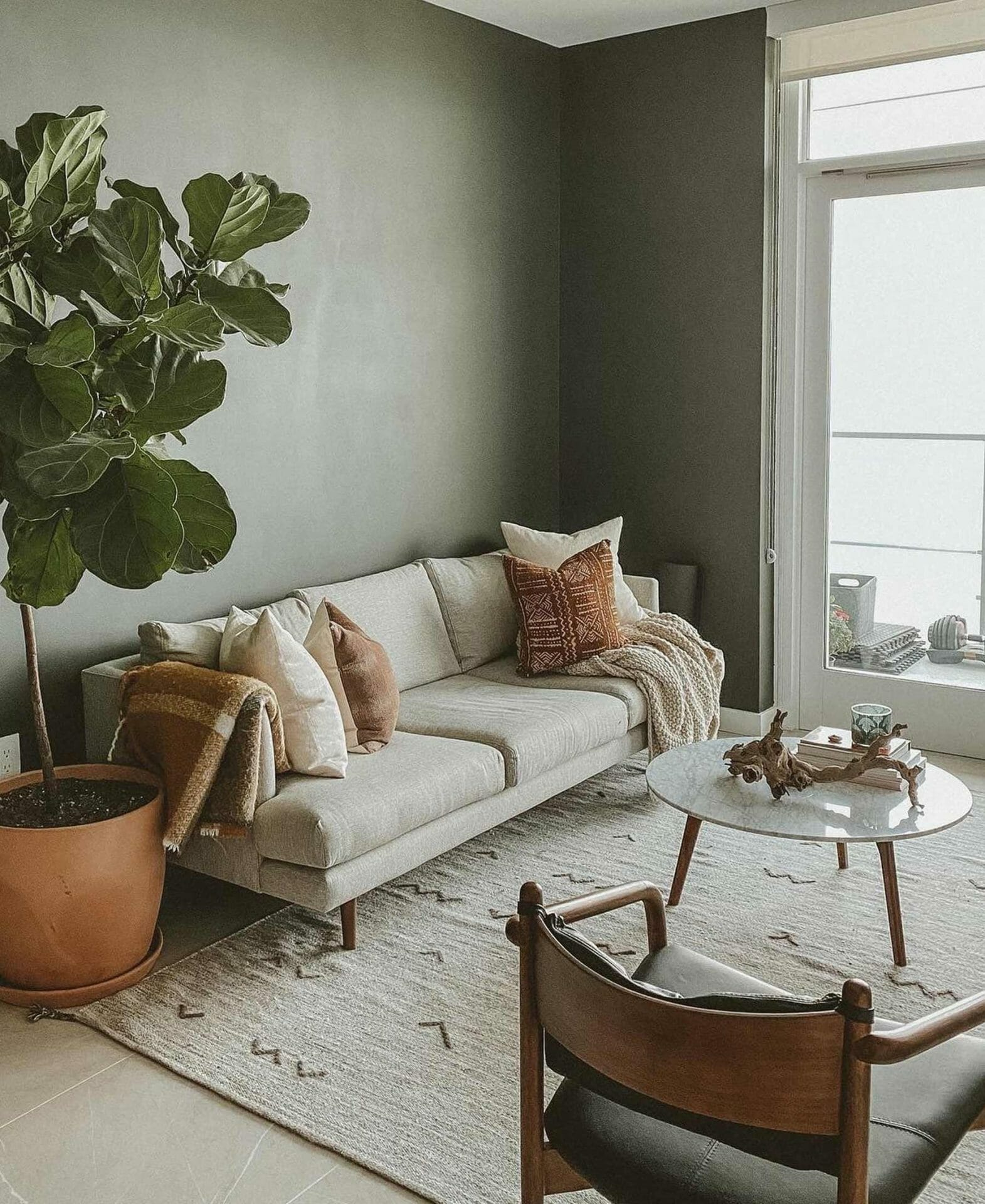 Ruang tamu minimalis Blogger Travis Collins dilengkapi dengan sofa ringan, fiddle leaf fig, kursi kulit, dan meja kopi marmer.