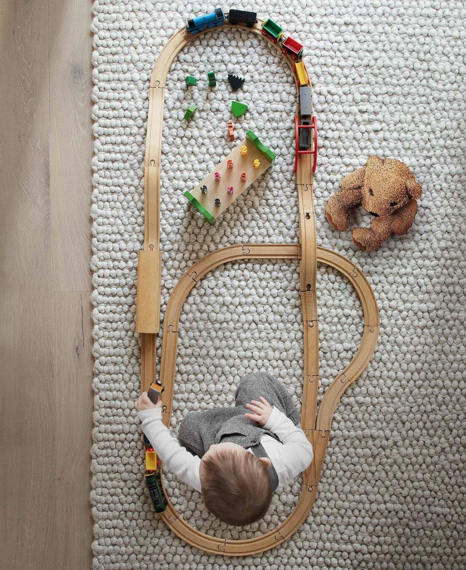 Phil Cohen's son plays with a wooden train track on the wool Hira Rug by Article.