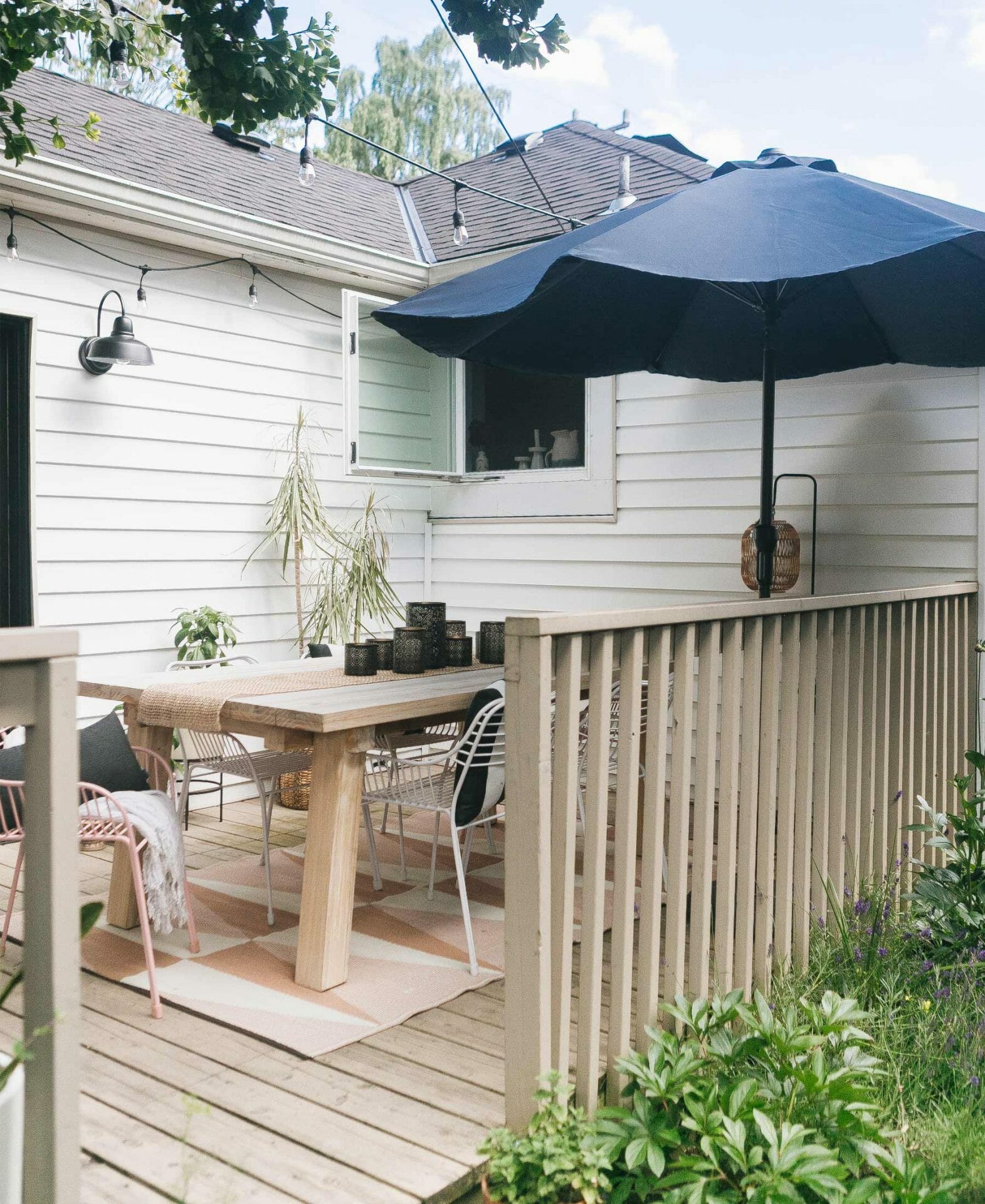 A large navy Paras outdoor umbrella is shown on a wooden porch.